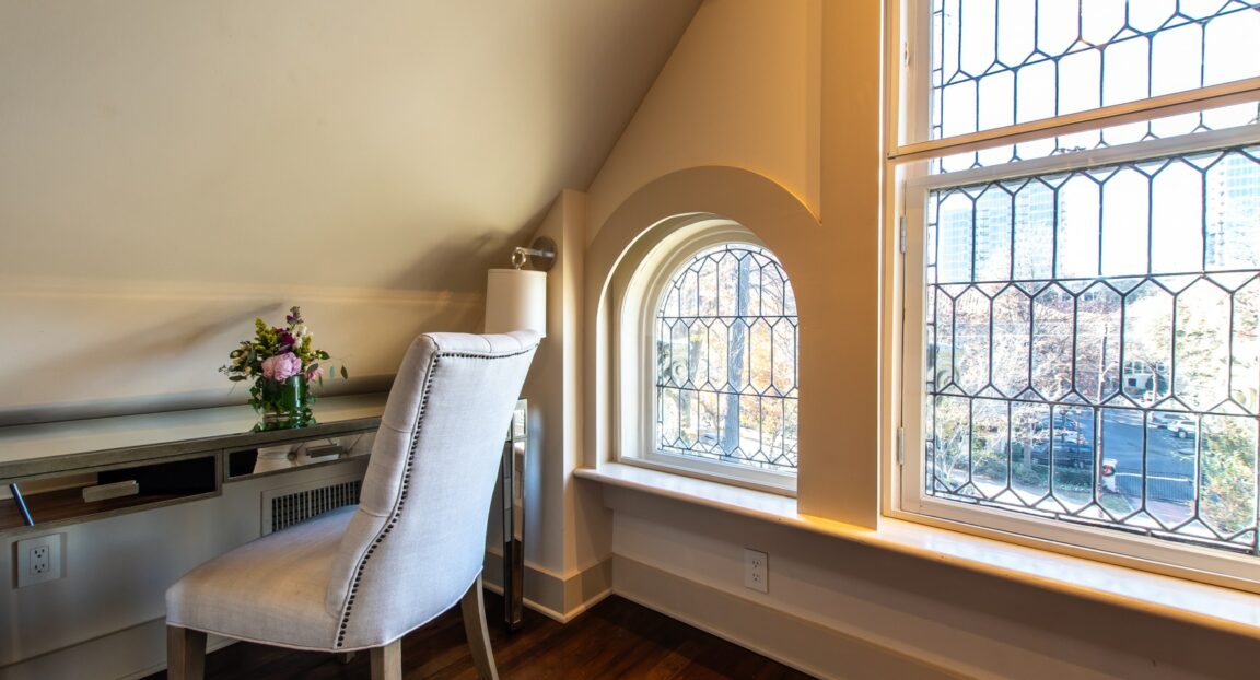 Eaves room with desk chair and mirrored desk next to arched windows